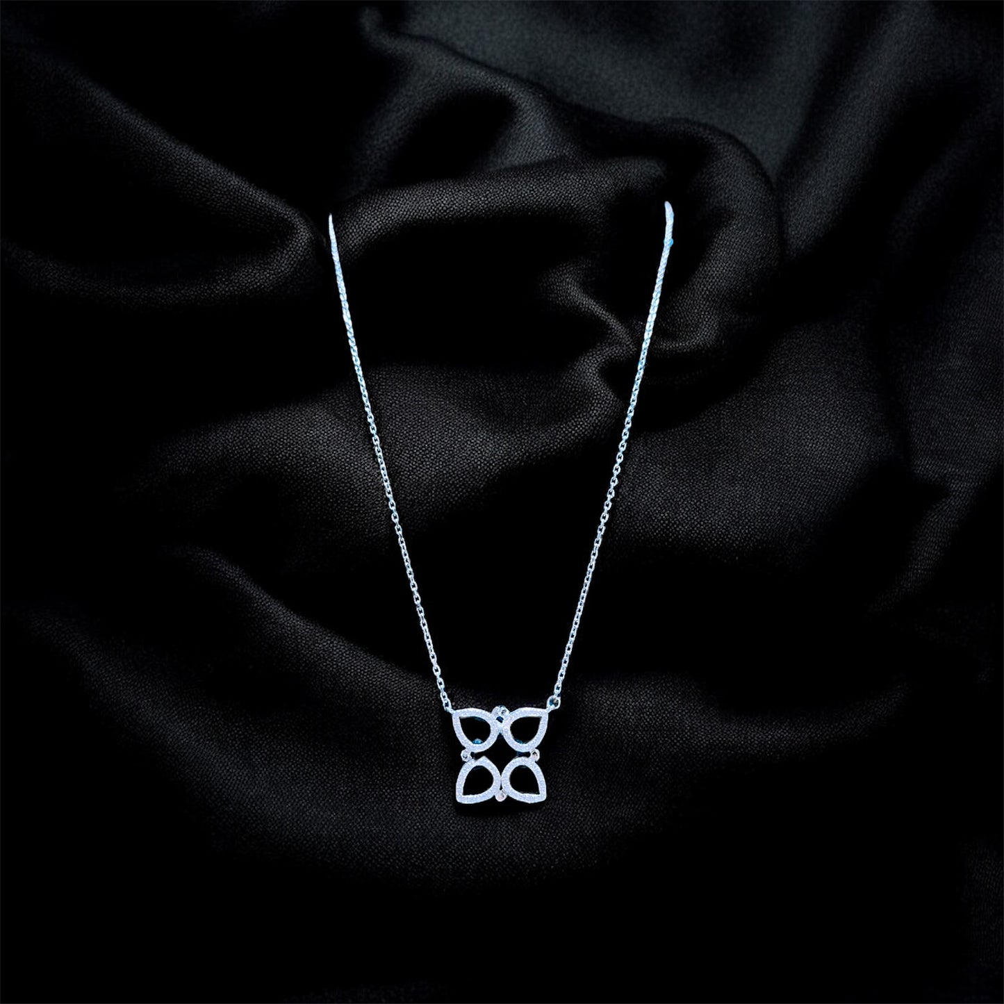 Silver necklace with a butterfly pendant on a black satin background