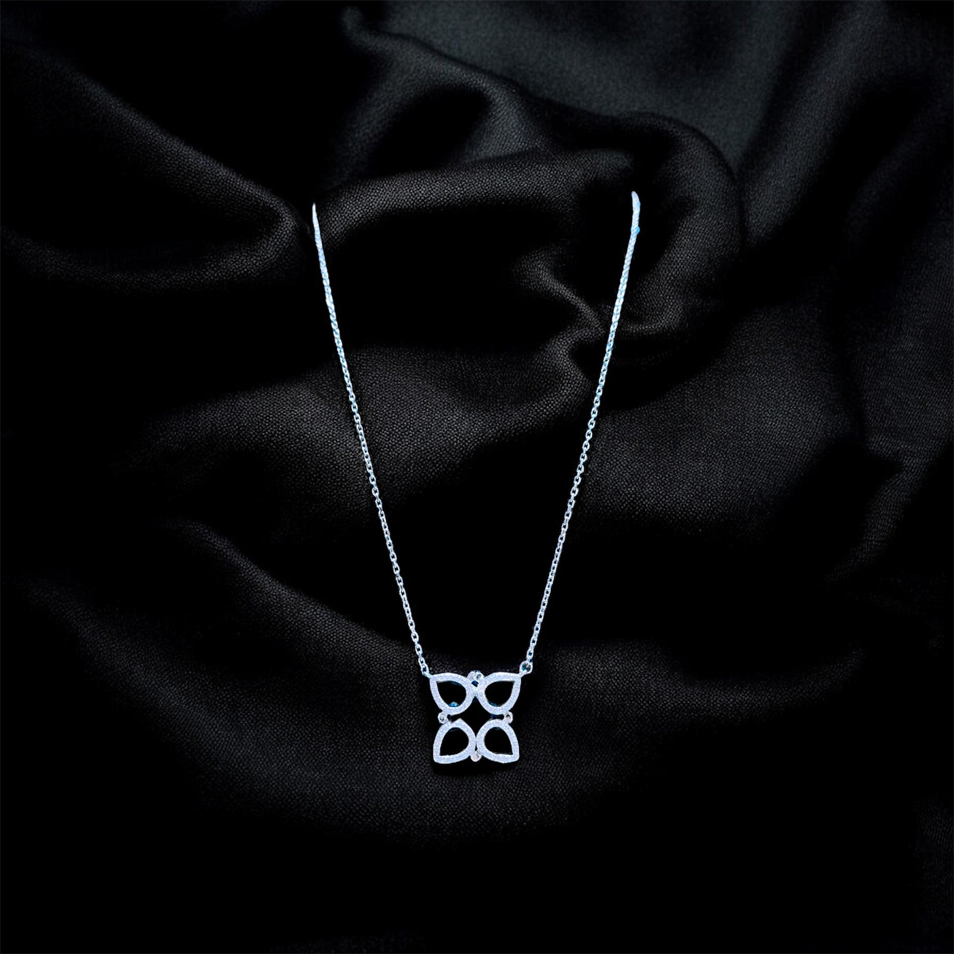 Silver necklace with a butterfly pendant on a black satin background