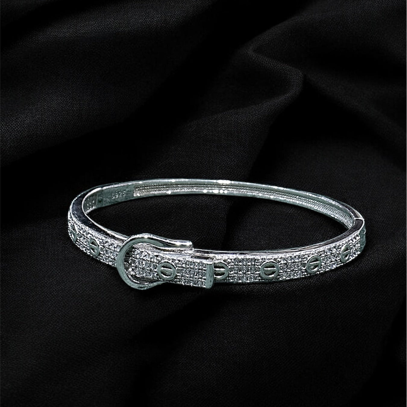 Silver bracelet with a clasp on a black fabric background