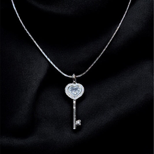 Silver key-shaped pendant necklace on a dark fabric background