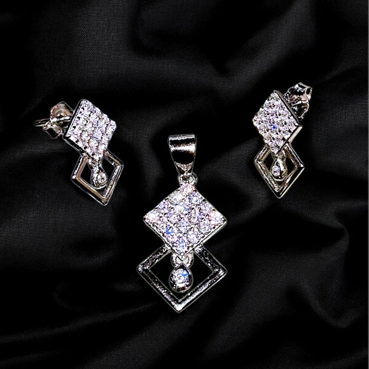 Silver jewelry set with diamond-like stones on a black fabric background