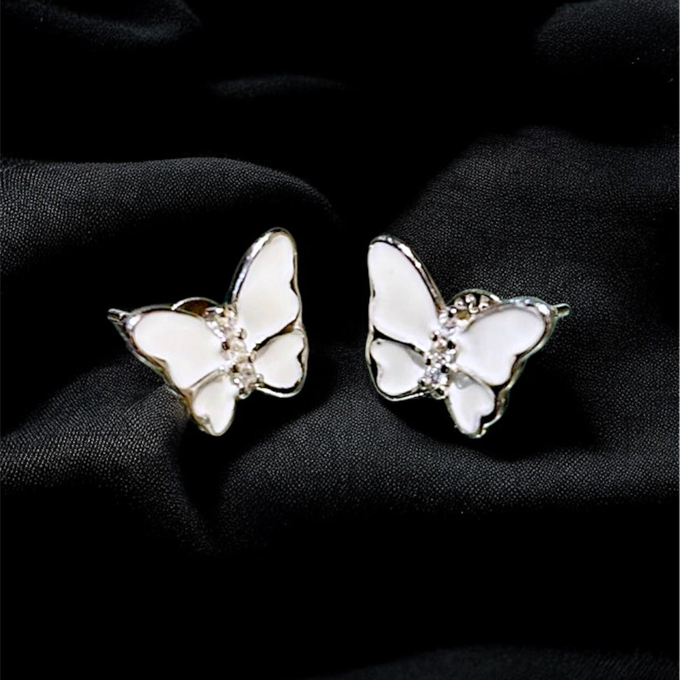 Butterfly-shaped earrings on a black fabric background