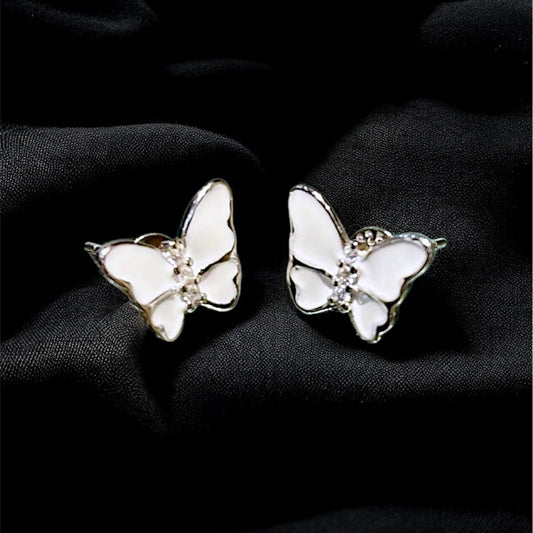 Butterfly-shaped earrings on a black fabric background