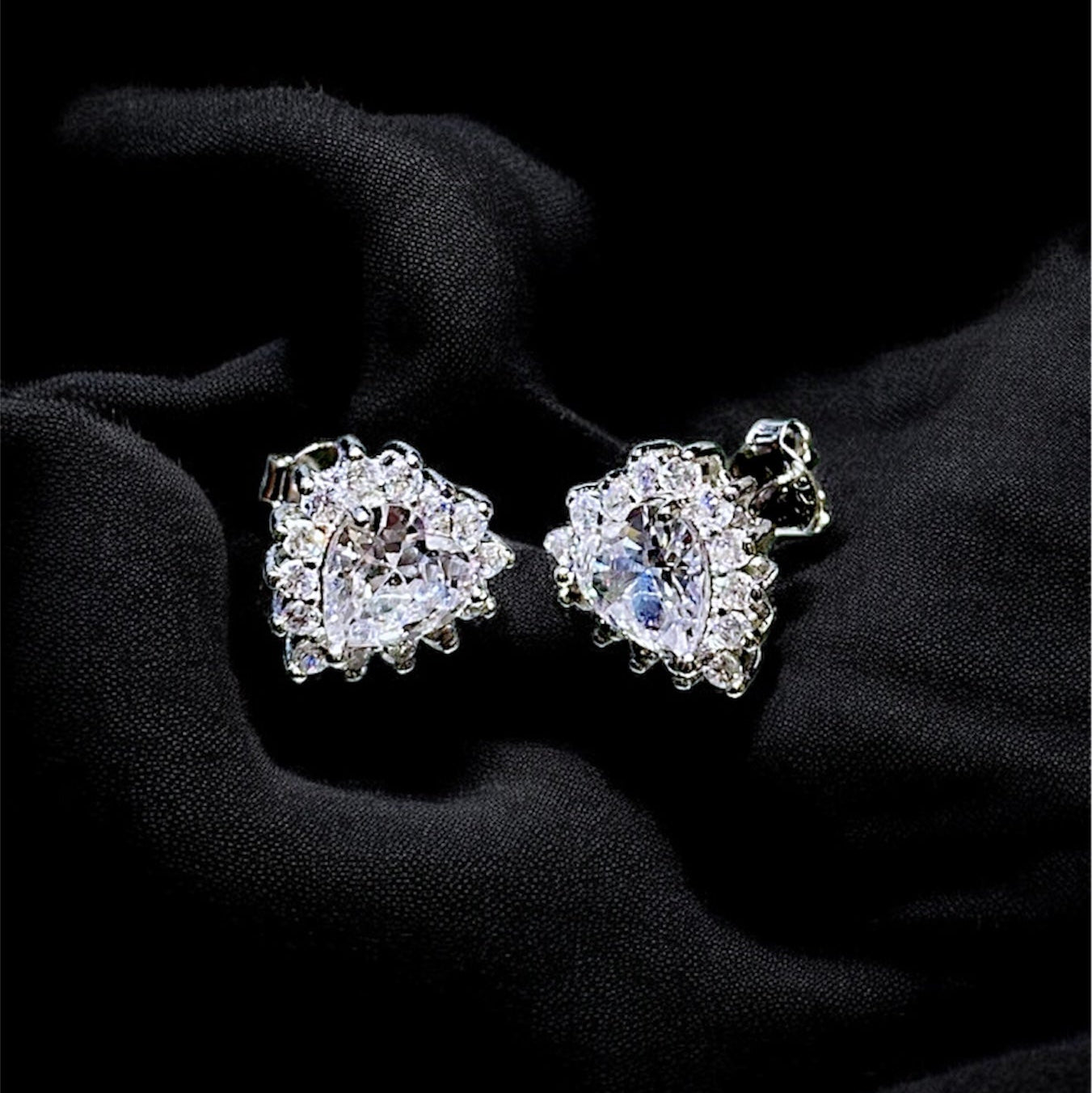 Pair of diamond earrings on a black fabric background