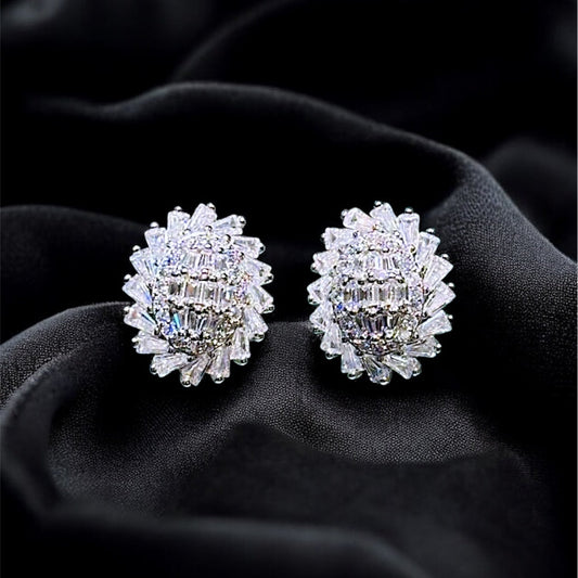 Pair of silver earrings with clear stones on a black fabric background