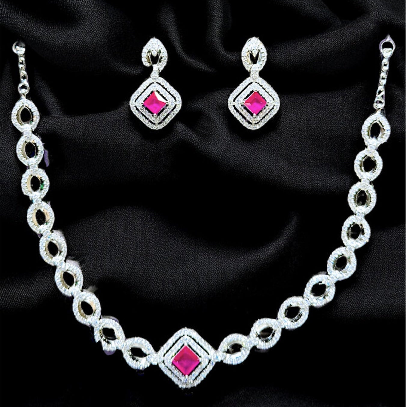 Jewelry set with necklace and earrings featuring pink gemstones on a black background