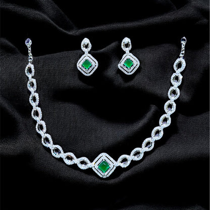 Jewelry set with necklace and earrings featuring green gemstones on a black fabric background