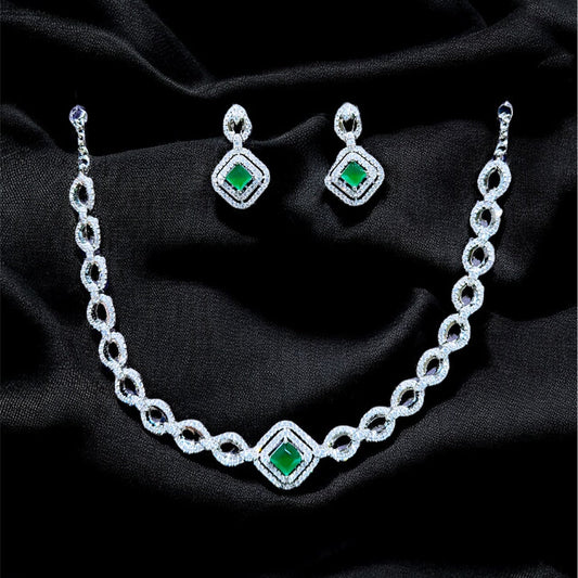 Jewelry set with necklace and earrings featuring green gemstones on a black fabric background