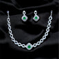 Jewelry set with necklace and earrings featuring green gemstones on a black fabric background