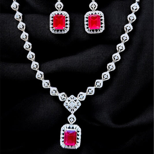 Jewelry set with necklace and earrings featuring red gemstones on a dark background