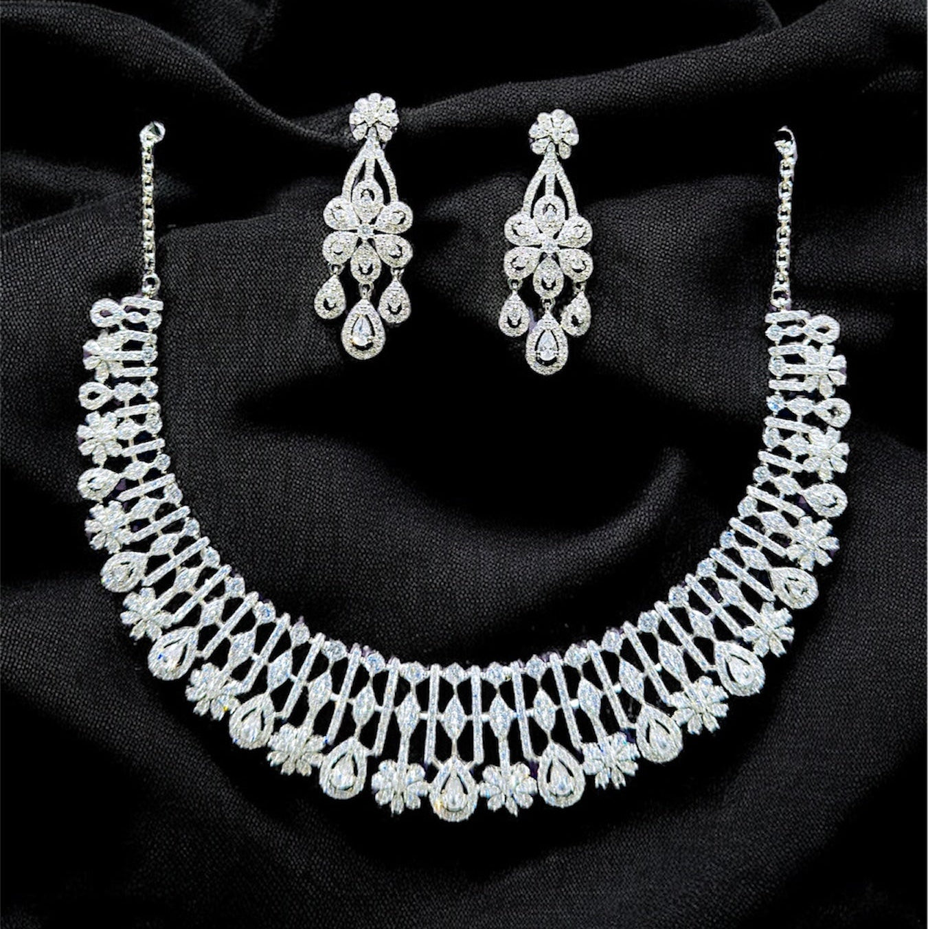 Silver necklace and earrings on a black fabric background