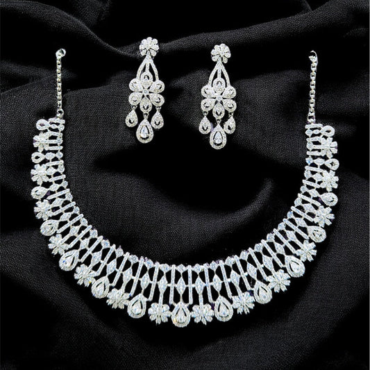 Silver necklace and earrings on a black fabric background