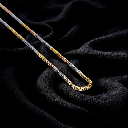 Two gold chains on a dark textured fabric background