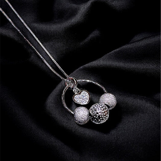 Silver necklace with spherical pendants on a black fabric background
