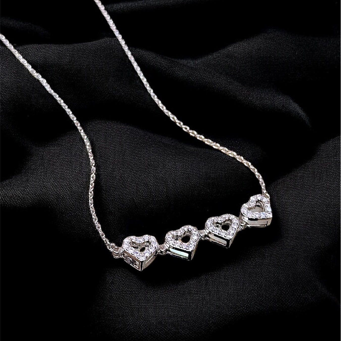 Silver necklace with heart-shaped pendants on a black background