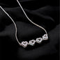 Silver necklace with heart-shaped pendants on a black background