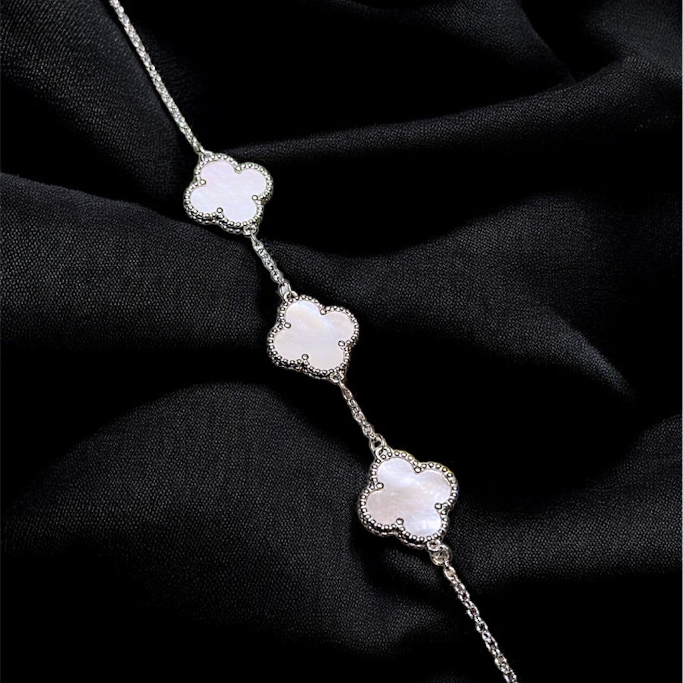 Silver bracelet with floral designs on a black fabric background