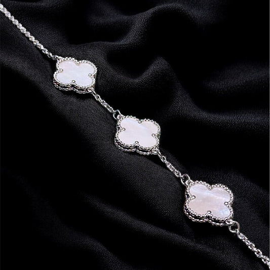 Silver necklace with three floral pendants on a black fabric background