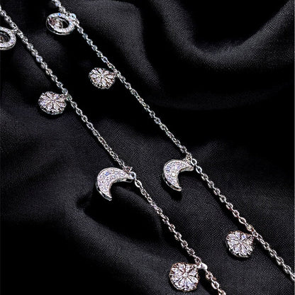 Silver necklace with moon and star pendants on a black fabric background