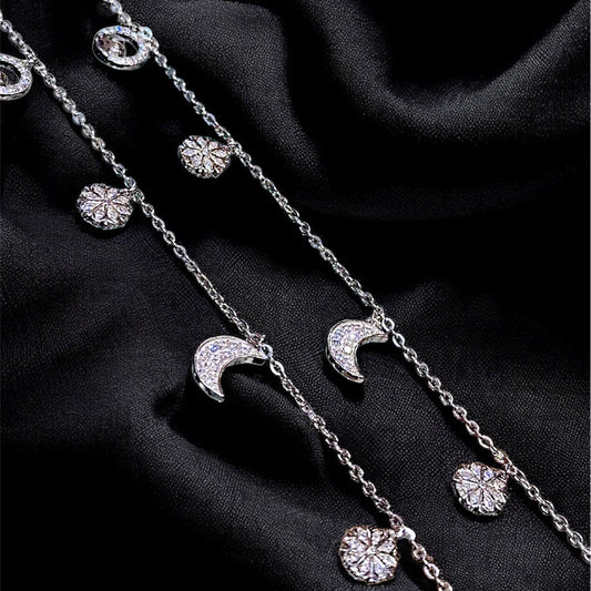 Silver necklace with moon and star pendants on a black fabric background