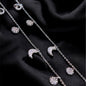 Silver necklace with moon and star pendants on a black fabric background