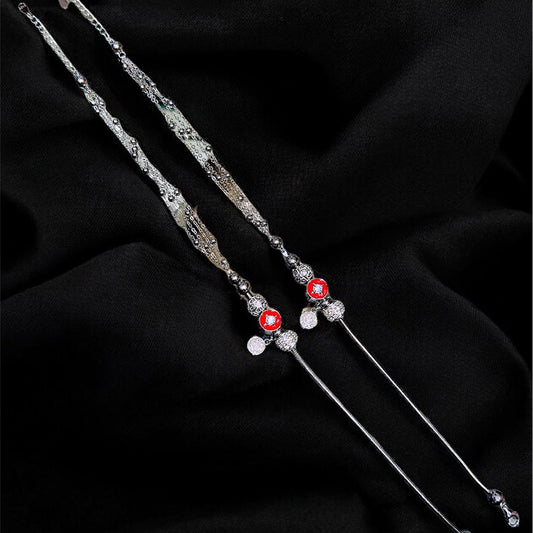 Silver hairpins with red and clear beads on a black fabric background