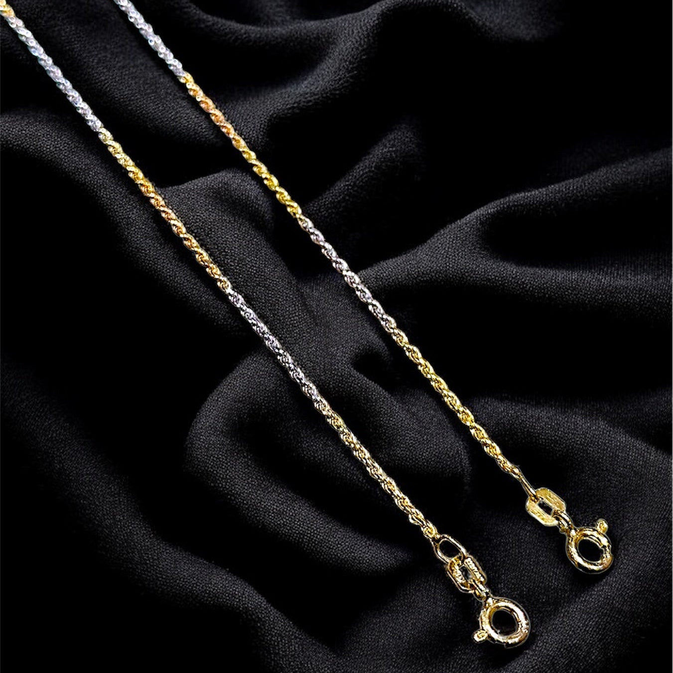 Two gold necklaces on a black fabric background