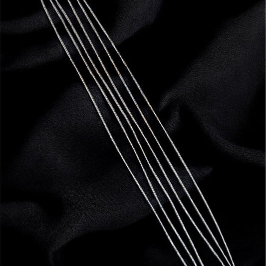 Three silver necklaces on a black fabric background