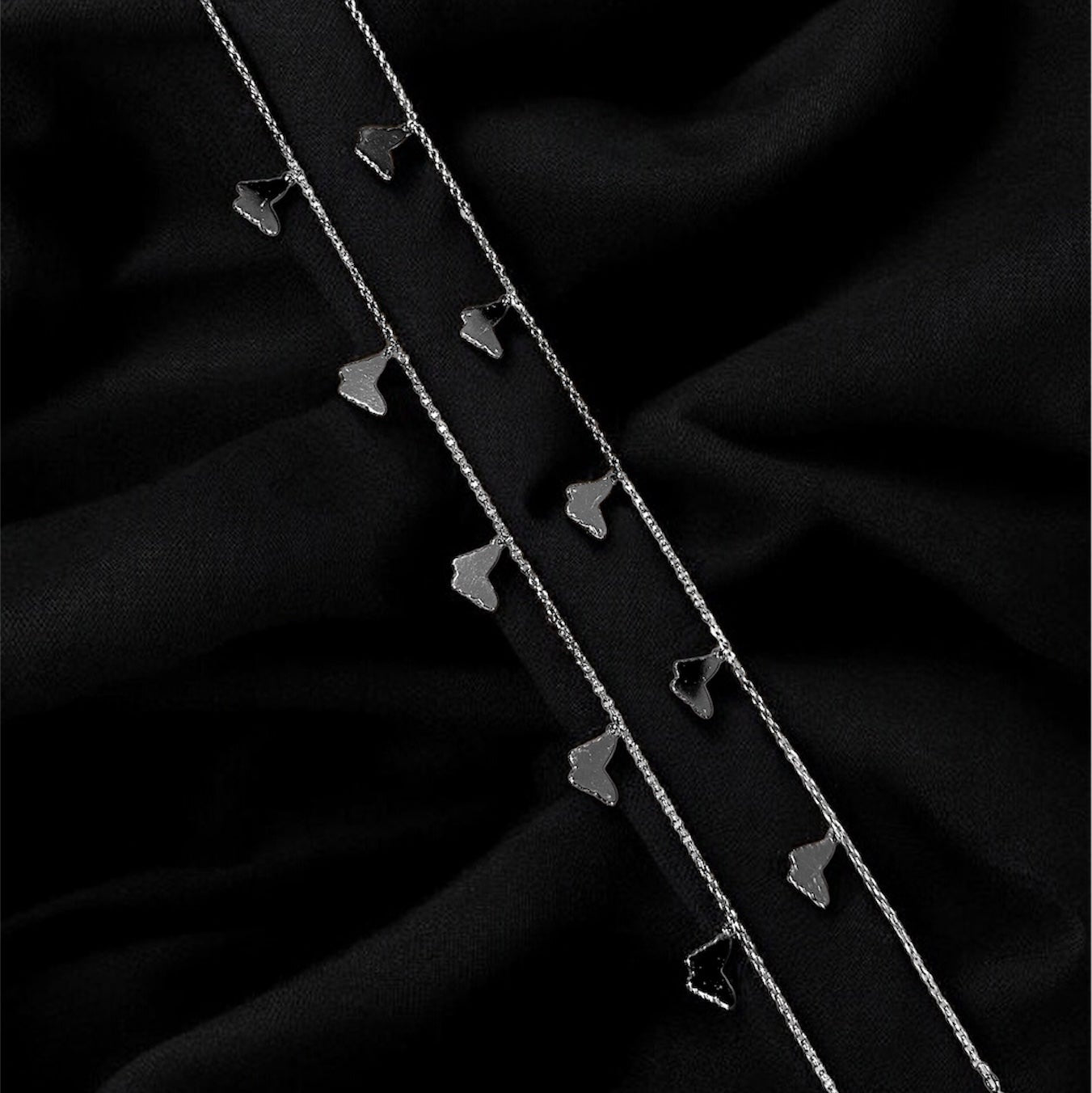 Two silver hairpins on a black fabric background
