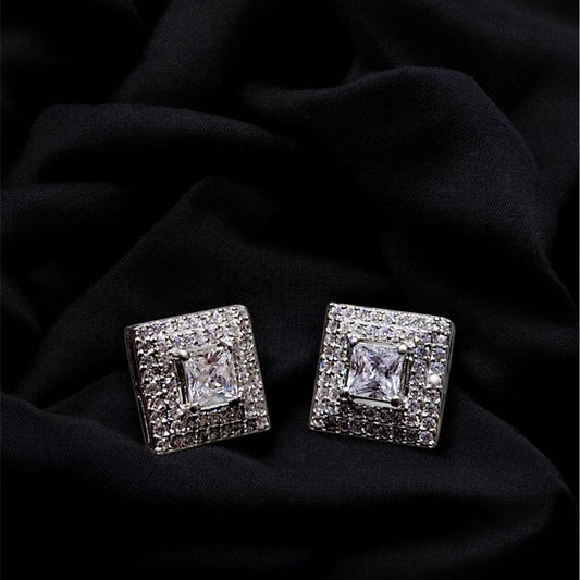 Pair of square-shaped diamond earrings on a black fabric background