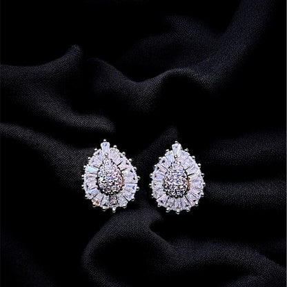 Pair of teardrop-shaped earrings with gemstones on a black fabric background