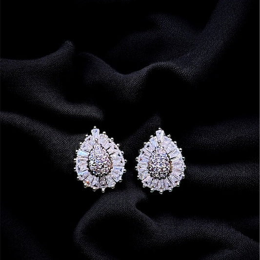 Pair of teardrop-shaped earrings with gemstones on a black fabric background