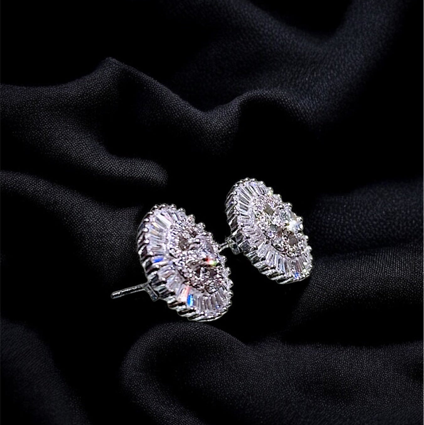 Pair of silver earrings on a black fabric background