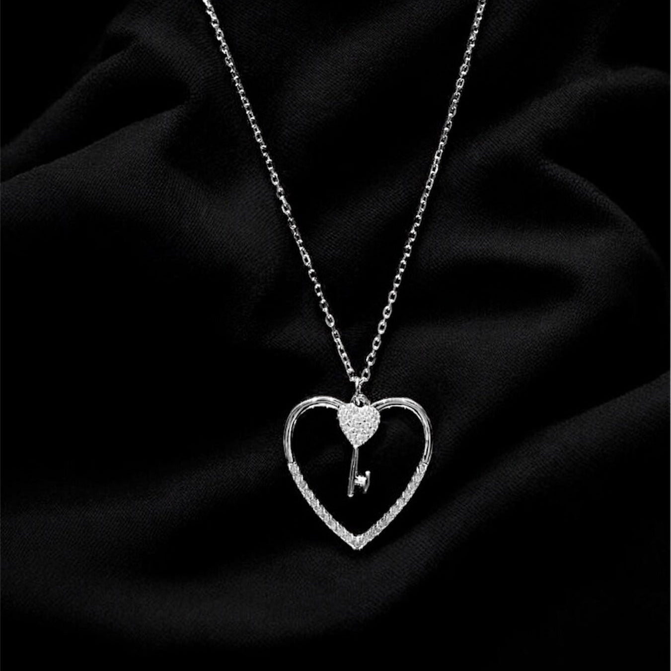 Silver necklace with a heart-shaped pendant on a black fabric background