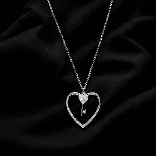 Silver necklace with a heart-shaped pendant on a black fabric background