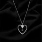 Silver necklace with a heart-shaped pendant on a black fabric background