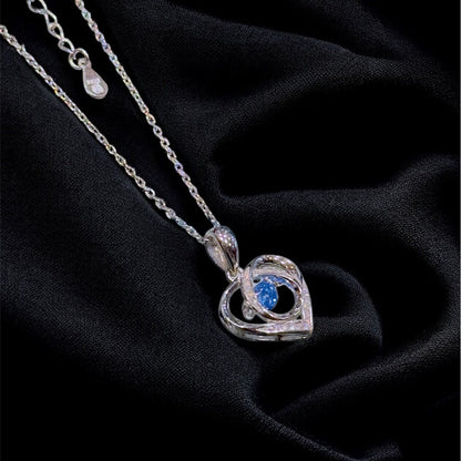 Silver necklace with a heart-shaped pendant on a black fabric background