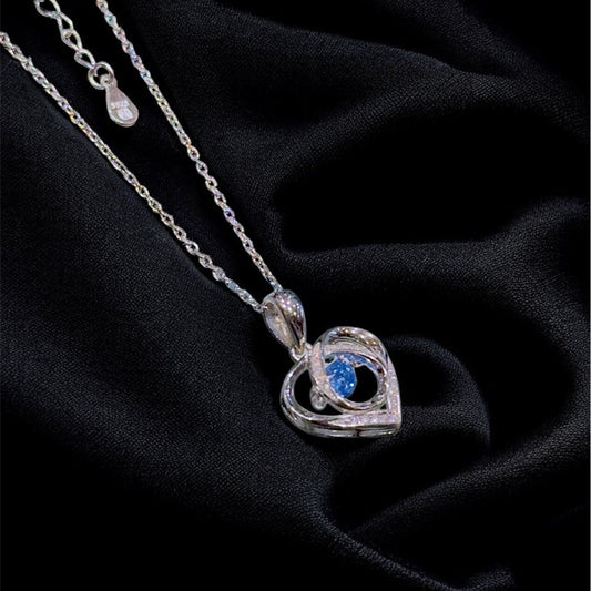 Silver necklace with a heart-shaped pendant on a black fabric background