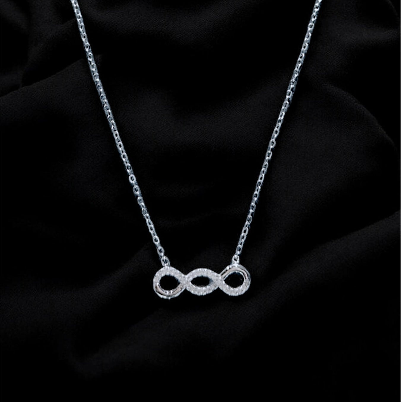 Silver necklace with a unique pendant on a black fabric background