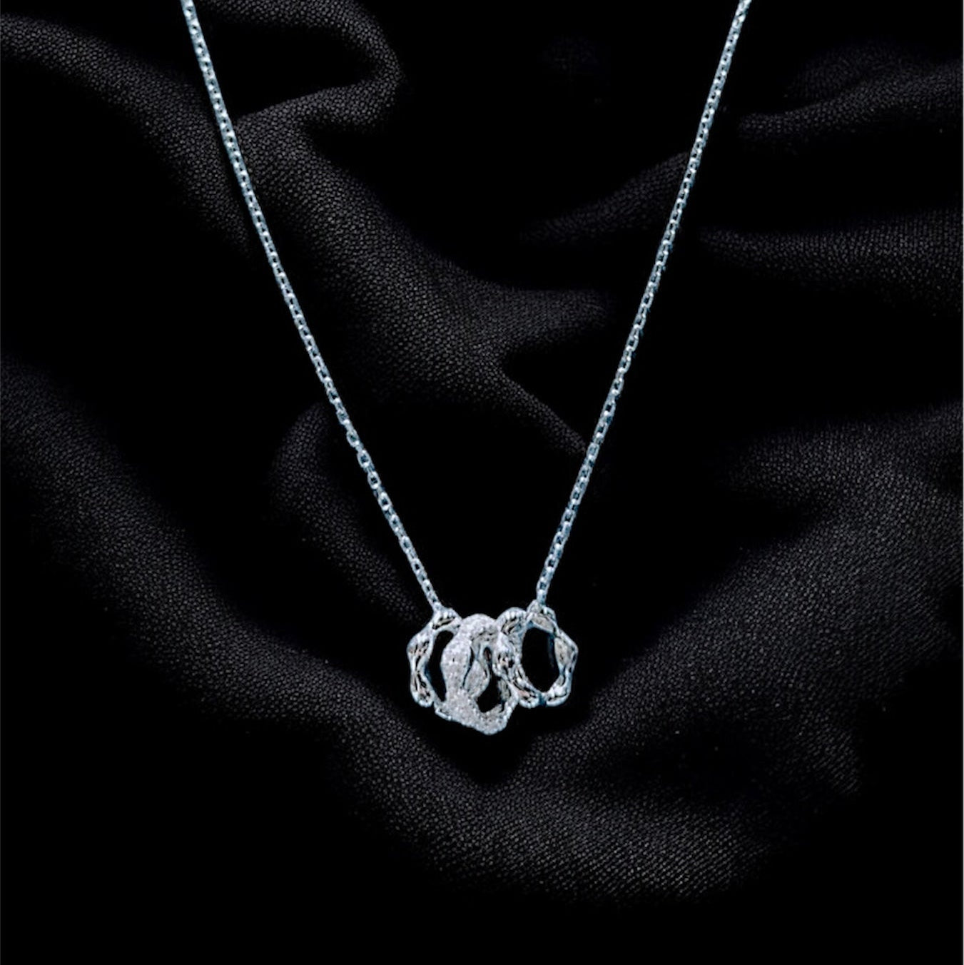 Silver necklace with a pendant on a black fabric background