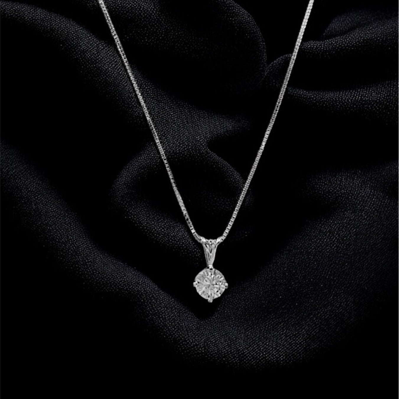 Silver necklace with a pendant on a black fabric background