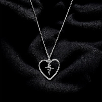 Silver necklace with a heart-shaped pendant on a black fabric background