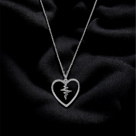 Silver necklace with a heart-shaped pendant on a black fabric background