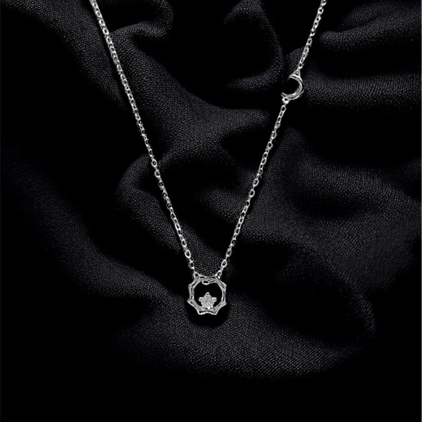 Silver necklace with a heart pendant on a dark fabric background