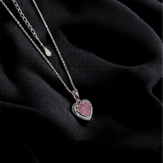 Silver necklace with a heart-shaped pendant on a black fabric background