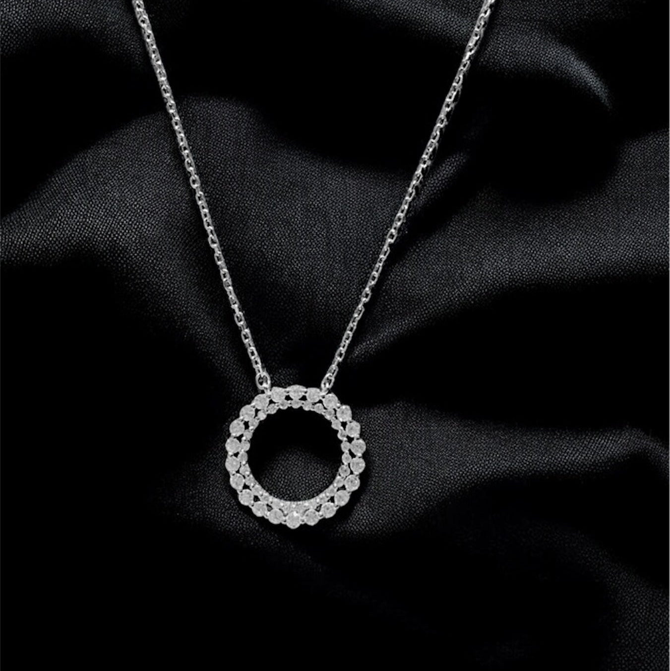 Silver necklace with a circular pendant on black fabric