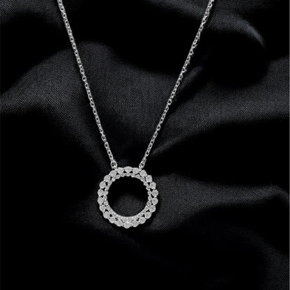 Silver necklace with a circular pendant on black fabric