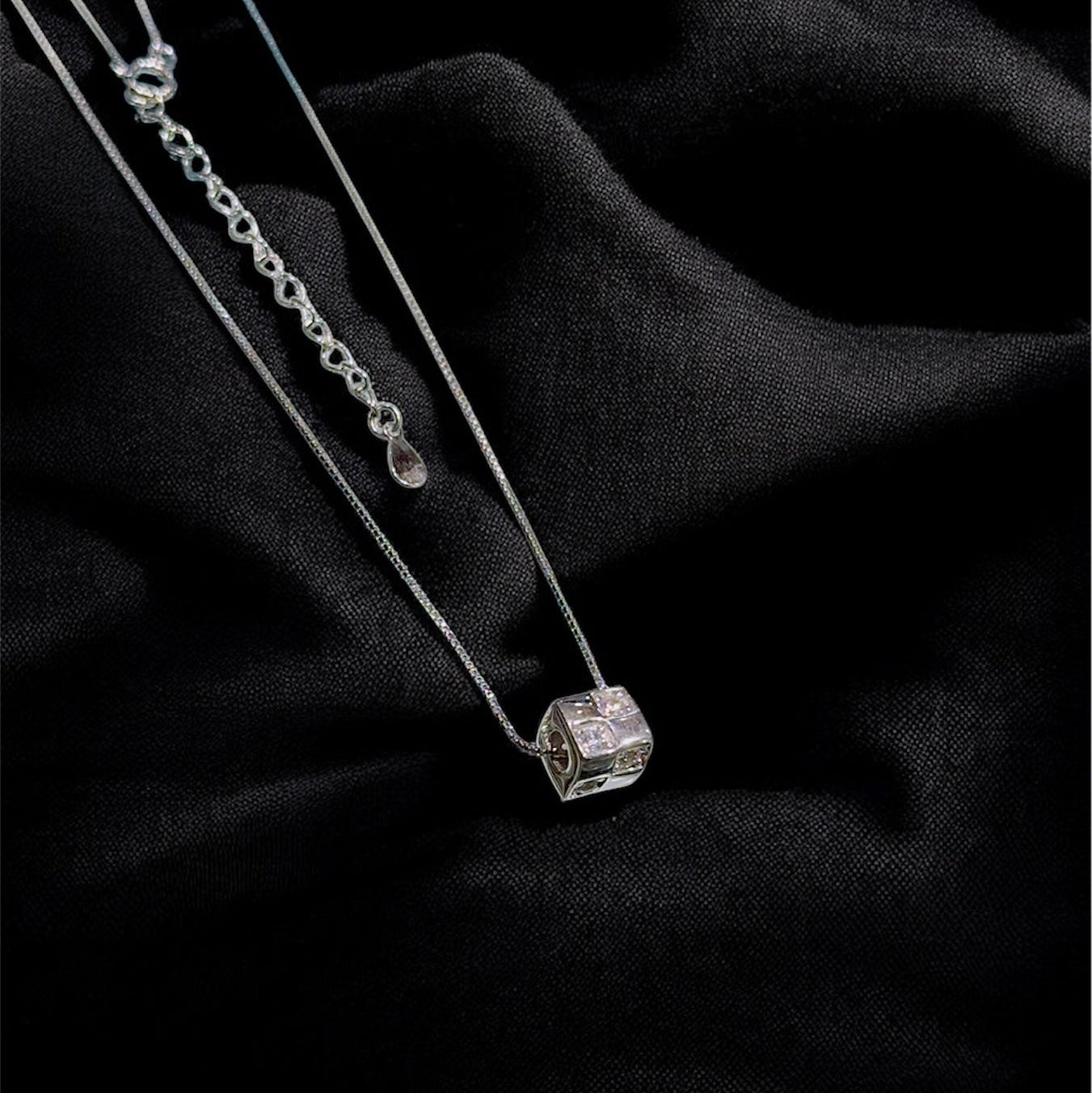 Silver necklace with a diamond pendant on a black fabric background