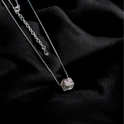 Silver necklace with a diamond pendant on a black fabric background