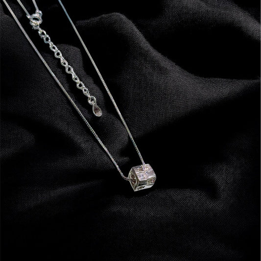 Silver necklace with a diamond pendant on a black fabric background